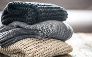 A stack of neatly folded chunky knit sweaters